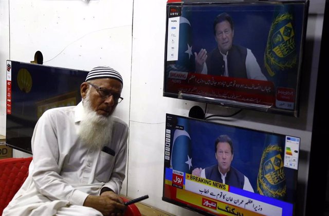 Un hombre junto a unas pantallas de televisión con la imagen del primer ministro paquistaní, Imran Jan