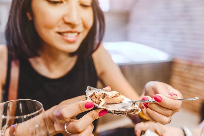 Mujer comiendo ostras.