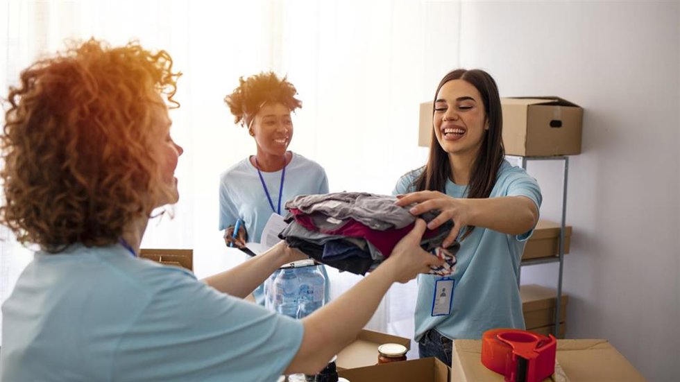 Archivo - Volunteers Collecting Food Donations In Warehouse. Happy team of volunteers holding donations boxes in a large warehouse. Volunteers putting clothes in donation boxes, social worker making notes charity
