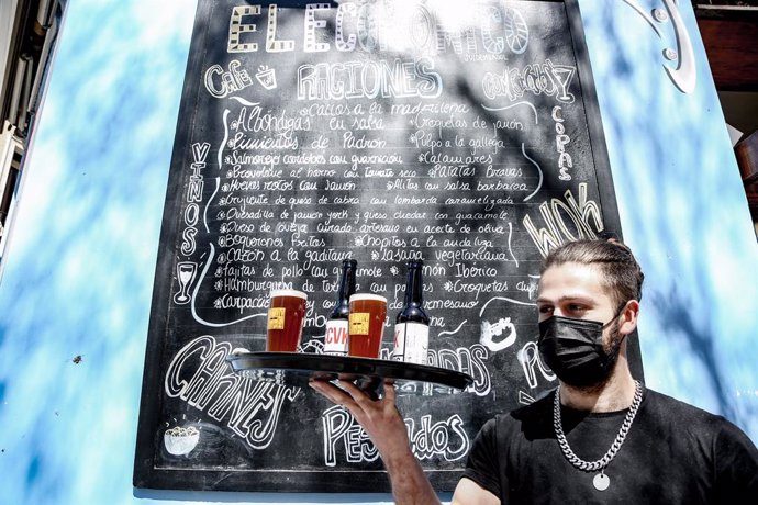 Un camarero lleva cervezas artesanales en una terraza, en uno de los bares que participan en Artesana Week Lavapiés, en la calle Argumosa, a  2 de abril de 2022, en Madrid (España). 