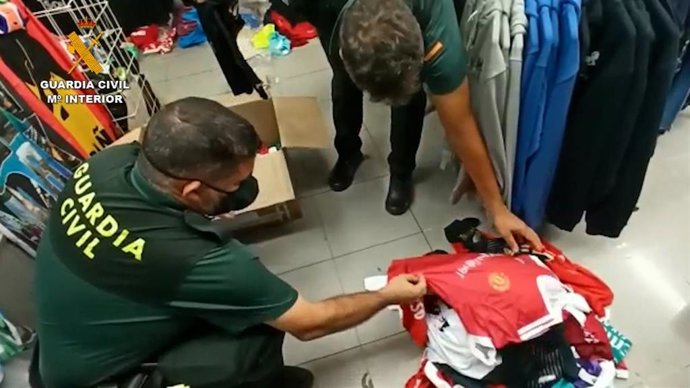 Agente de la Guardia Civil inspeccionando prendas supuestamente falsificadas