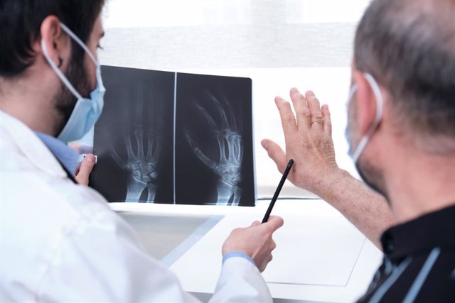 Médico enseñando una radiografía a un paciente en la consulta.
