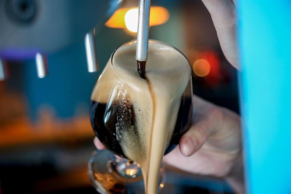 Una camarera tira una cerveza negra artesanal en un bar