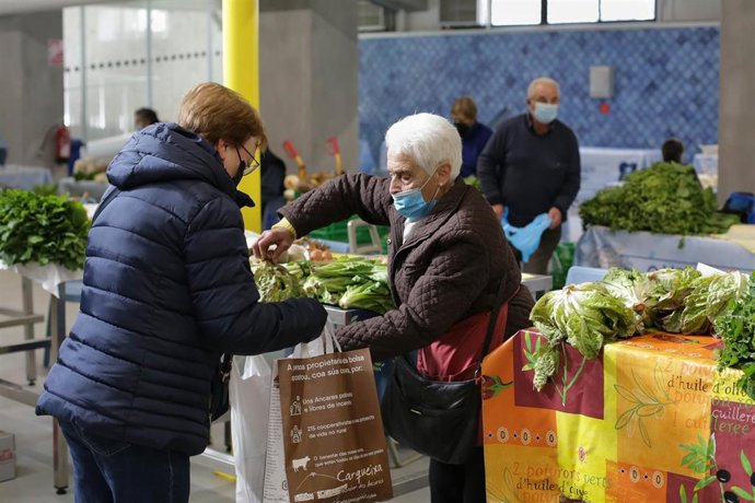 Una mujer compra verduras en un puesto local en una imagen de archivo.