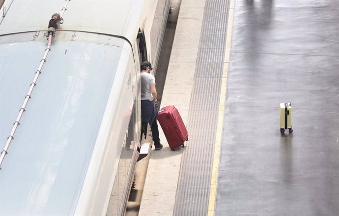 Un hombre con una maleta sube a un tren en la Estación Puerta de Atocha, a 13 de abril de 2022, en Madrid