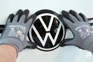 Archivo - Un empleado cologa un logo de Volkswagen en un vehículo