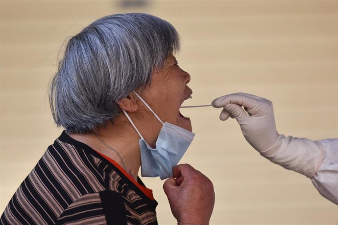 Un trabajador sanitario con equipo de protección personal recoge muestras de hisopo de un residente. 