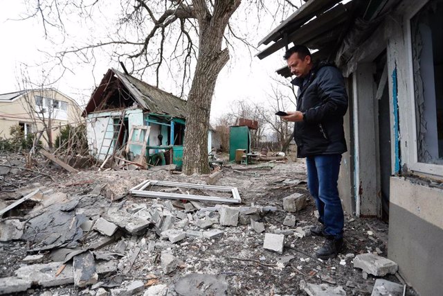 Archivo - Un residente local se encuentra cerca de una casa dañada en Donetsk, en el este de Ucrania