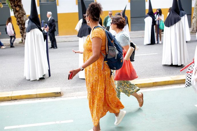 Unas turistas viendo la Hermandad de la Sed, en la Av, Luis Montoto, en  la Semana Santa Sevilla 2022. Miércoles Santo a 13 de abril 2022 en Sevilla (Andalucía, España)