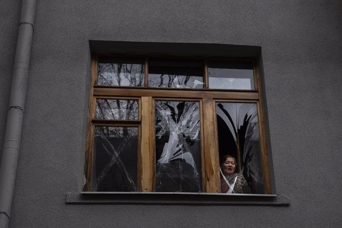 April 17, 2022, Kharkiv, Ukraine: A woman peers through a broken glass window after Russia shelled the building across the street in Kharkiv, Ukraine on April 17, 2022. At least five people were killed an 13 were wounded as Russia stuck the city multipl