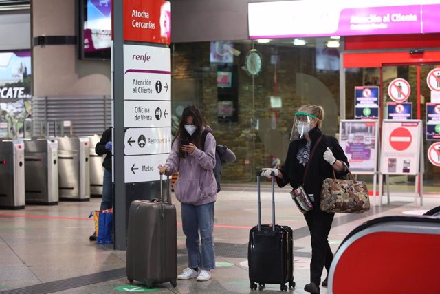 Archivo - Dos viajeros con mascarilla llegan con maletas a la estación de Atocha en Madrid (España), a 14 de mayo de 2020.