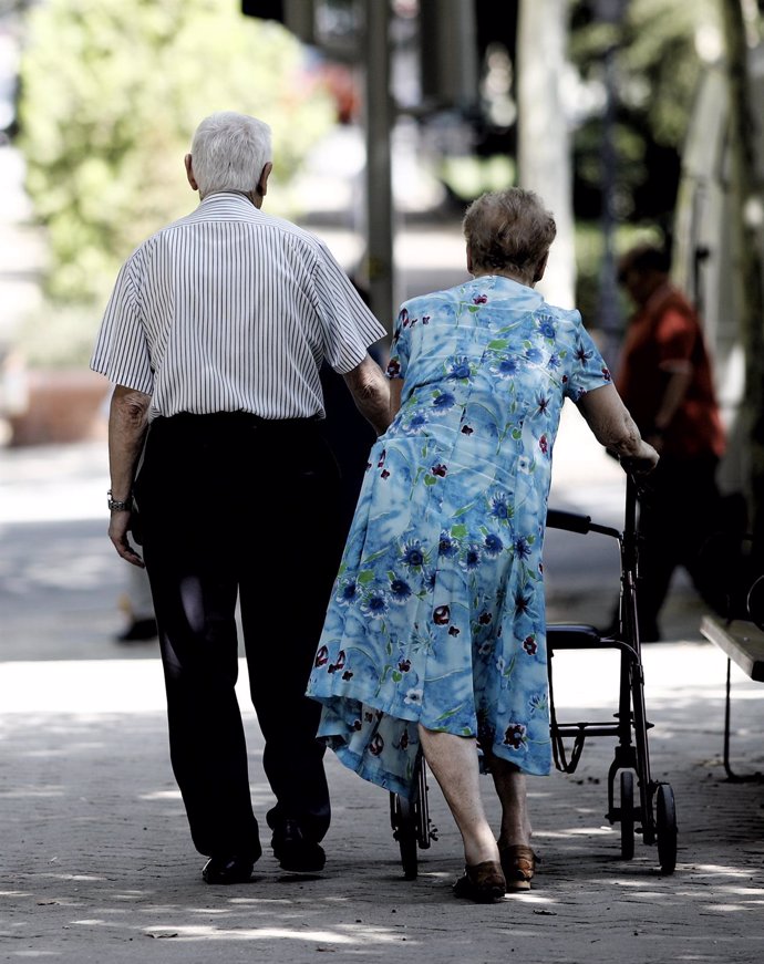 Archivo - Una pareja de pensionistas pasea por un parque de Madrid