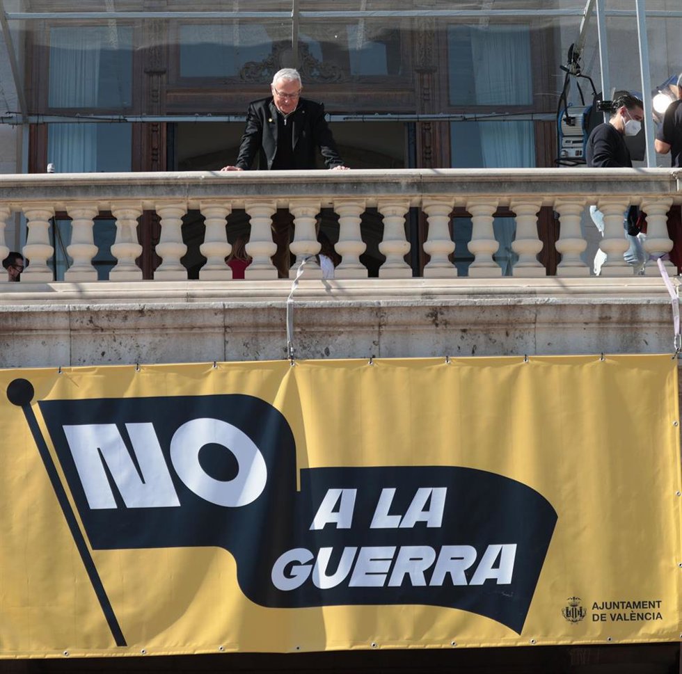 Archivo - Imagen de archivo del alcalde de Valncia, Joan Ribó, observando desde el balcón del Ayuntamiento la pancarta desplegada con el lema 'No a la guerra'.