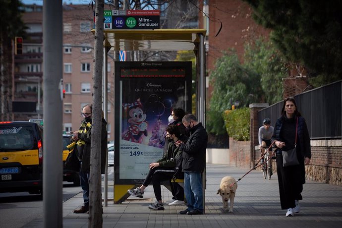 Archivo - Varias personas esperan el autobús en una parada de Barcelona a 17 de febrero de 2022 