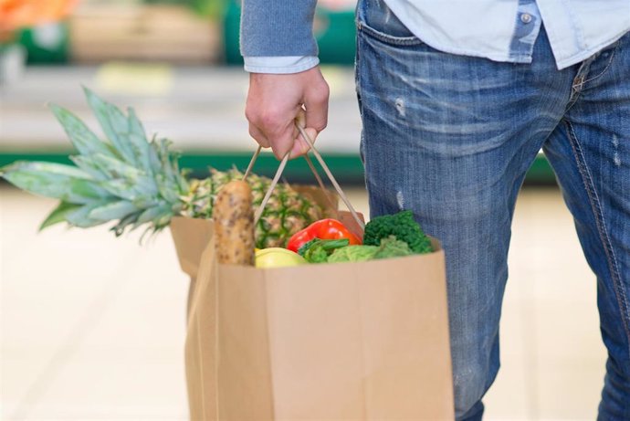 Archivo - Detalle de bolsa de papel cargada de fruta y verdura en un supermercado.
