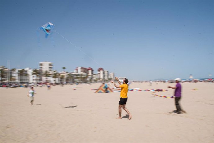 Varias personas participan en un festival de cometas en la playa de Gandia