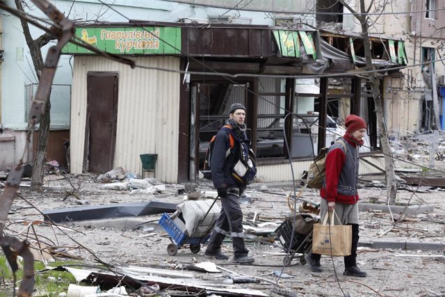 Dos residentes de la ciudad de Mariúpol caminan entre los escombros.