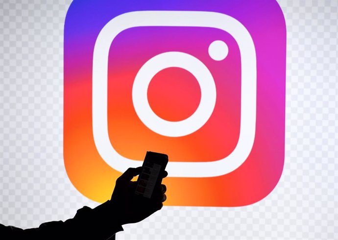 Archivo - FILED - 15 March 2019, Schleswig-Holstein, Aukrug-Homfeld: A man holds a smartphone in front of a monitor with the logo of Instagram. Photo: Carsten Rehder/dpa