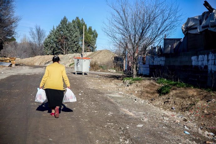 Archivo - Una mujer camina con bolsas que ha recogido en la entrega de regalos y alimentos organizada por la Fundación Madrina, en la Cañada Real, a 31 de diciembre de 2021, en Madrid, (España). 