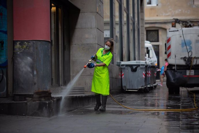 Archivo - Una trabajadora limpia una vía de Barcelona. ARCHIVO