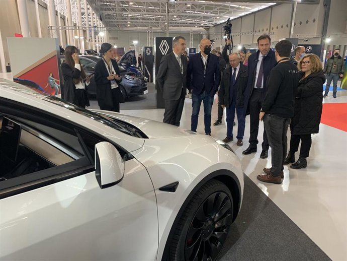 El alcalde de Valladolid y otras autoridades, junto a representantes de la Feria de Valladolid y de la empresa Zest, observan uno de los modelos de Tesla en el Salón del Automóvil Híbrido y Eléctrico.