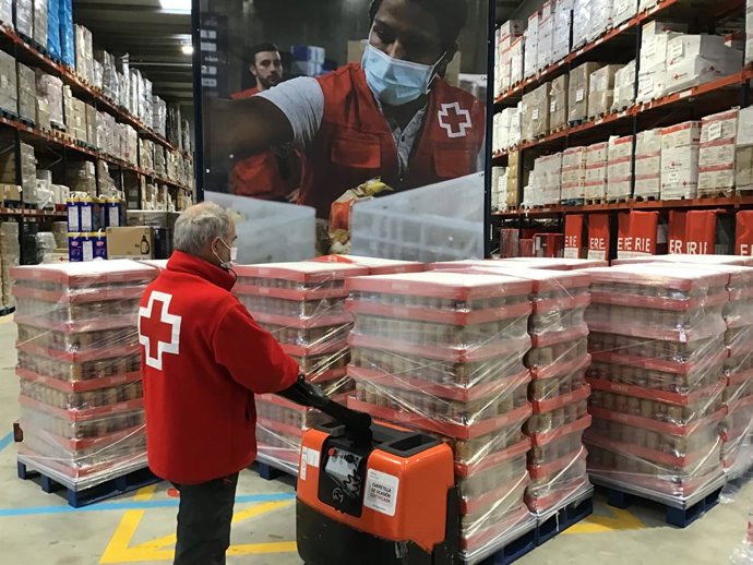 Archivo - Un membre de la Creu Roja transporta aliments donats.