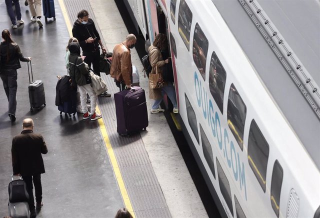 Varias personas, con maletas, en el andén antes de coger un tren de alta velocidad de Ouigo