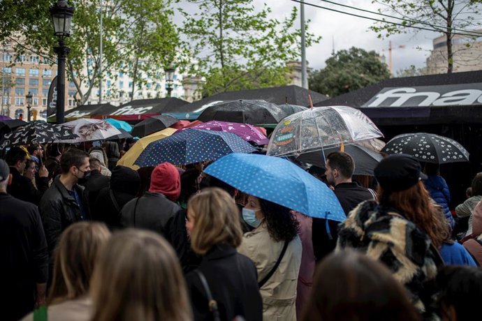 Diverses personis, amb paraigües, en la fira literria de Sant Jordi, en el dia Internacional del Llibre, a 23 d'abril de 2022, a Barcelona