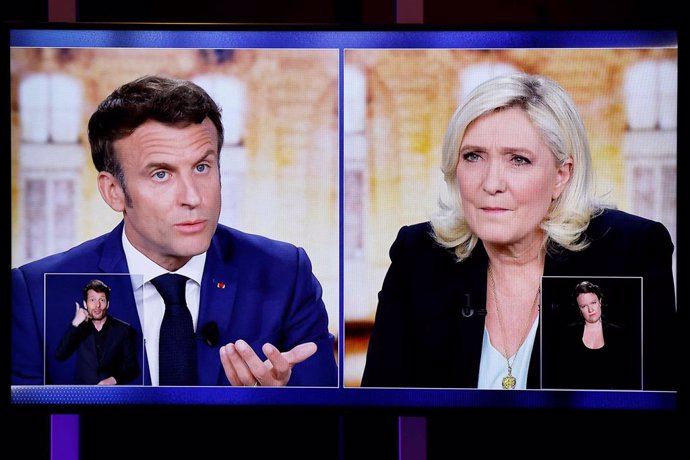 20 April 2022, France, Saint-Denis: A TV screen shows the televised debate on French TV channels between the French President and the liberal party La Republique en Marche (LREM) candidate for re-election Emmanuel Macron (L)and Marine Le Pen, president