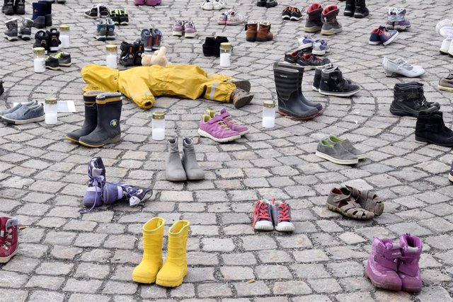 10 April 2022, Finland, Helsinki: Child's overall, shoes, boots and candles can be seen in a demonstration to honour the memory of the children killed in Mariupol during the Russian war in Ukraine. Photo: Jussi Nukari/Lehtikuva/dpa