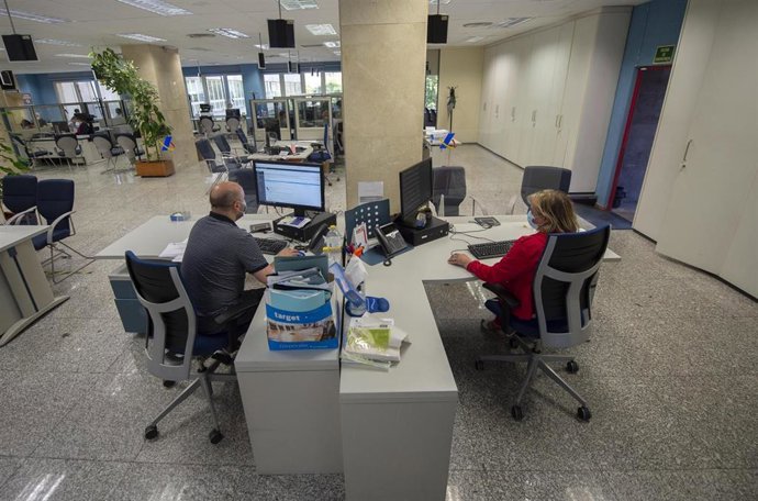 Archivo - Dos empleados en su puesto de trabajo de la Oficina de Hacienda de la Calle de Guzmán el Bueno, a 27 de julio de 2021, en Madrid, (España). El Gobierno prevé aprobar este martes en Consejo de Ministros una Oferta de Empleo Público (OPE) de más