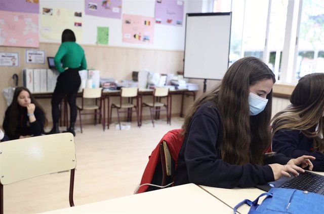 Una alumna, con mascarilla quirúrgica, trabaja con un ordenador portátil en un aula de un colegio
