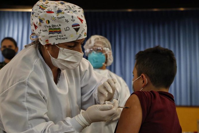 Archivo - Una trabajadora sanitaria vacuna a un niño en Bogotá, la capital de Colombia. 