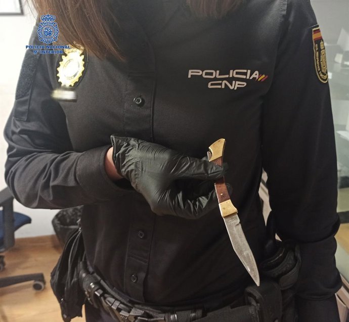 Un agente de la Policía Nacional sujeta la navaja incautada al detenido.