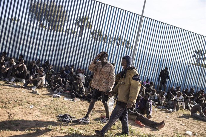 Archivo - Varios migrantes son atendidos por personal sanitario tras saltar la de Melilla el pasado 2 de marzo