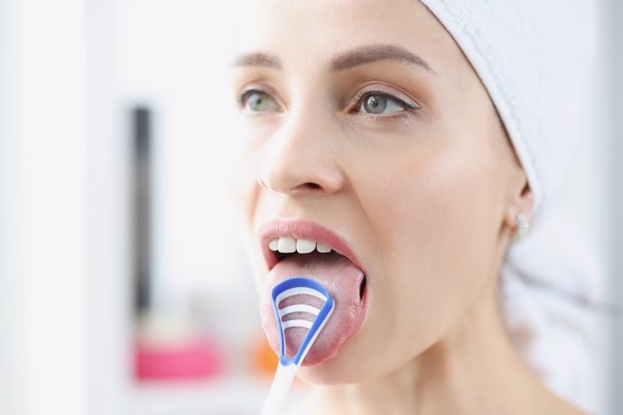 Archivo - Mujer se limpia la lengua con raspador especial