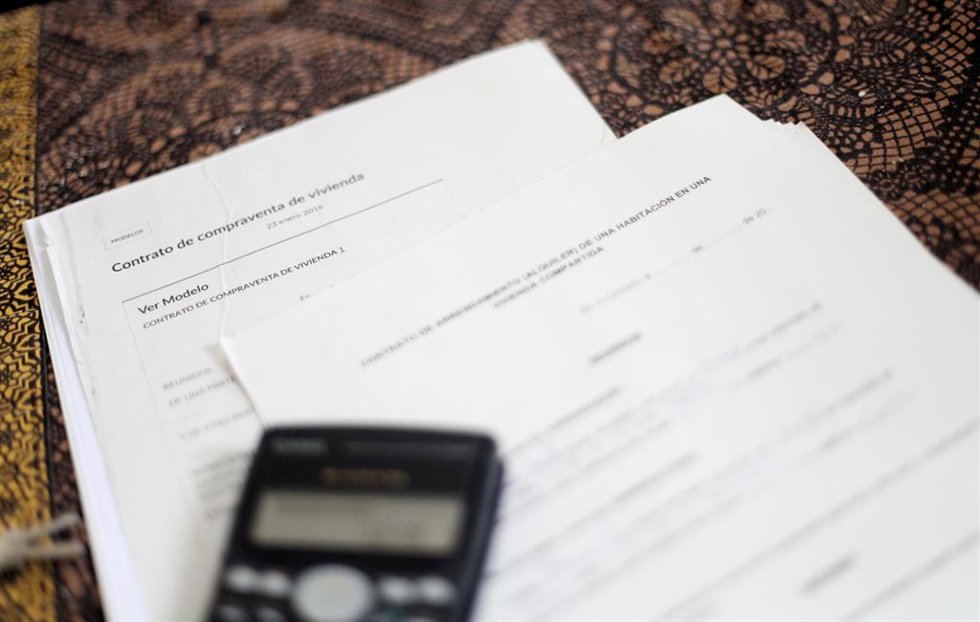 Archivo - Una calculadora sobre un contrato de compraventa de vivienda y un contrato de arrendamiento (alquiler) de una habitación en una vivienda compartida.