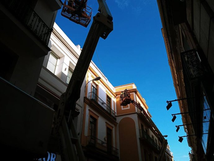 Varios operarios realizan mediciones en la calle Sierpes con vistas a la colocación de los nuevos toldos.