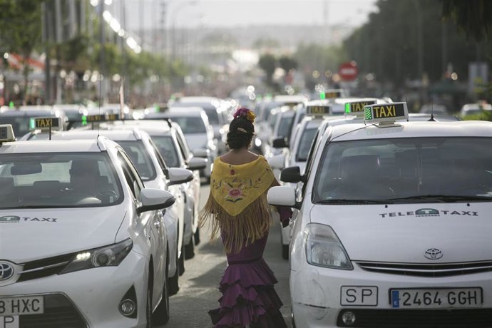Archivo - Una mujer vestida de flamenca en la parada de taxis de la Feria de Abril, en foto de archivo.