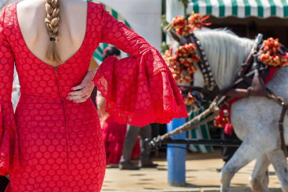 Archivo - Un mujer vestida de flamenca en el Real de la Feria, en una foto de archivo.