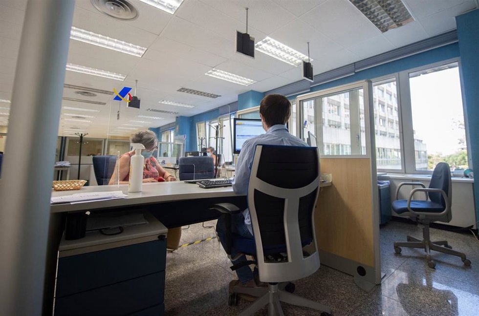 Archivo - Un empleado atiende a una mujer en su puesto de trabajo de la Oficina de Hacienda de la Calle de Guzmán el Bueno, a 27 de julio de 2021, en Madrid, (España). El Gobierno prevé aprobar este martes en Consejo de Ministros una Oferta de Empleo Pú