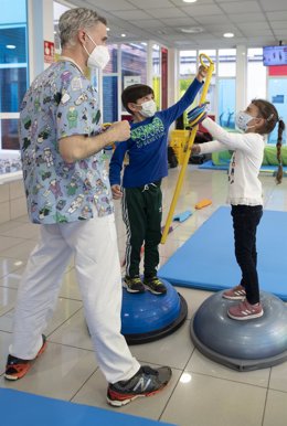 Archivo - Un fisioterapeuta aplica una terapia a dos niños.