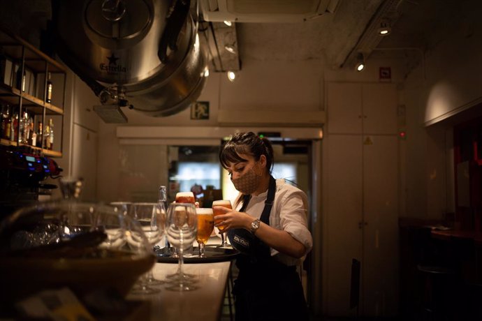 Archivo - Una camarera sirve una cerveza en el interior de un bar en una calle céntrica de Barcelona, a 14 de octubre de 2021, en Barcelona, Catalunya (España). A partir de este viernes en Cataluña se terminarán las limitaciones de aforo en los equipami