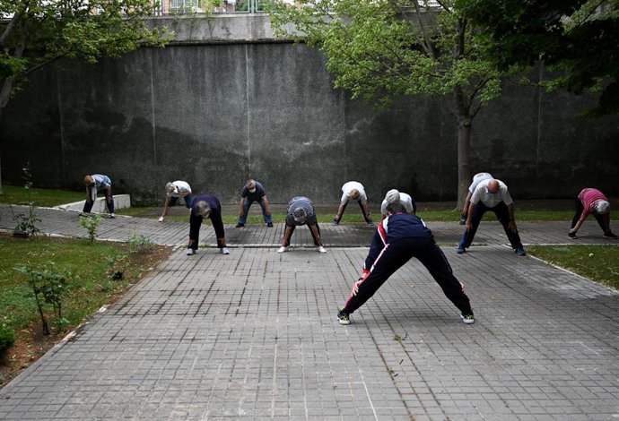 Archivo - Un grupo de ancianos realiza ejercicio en el jardín de un centro de día de personas mayores.