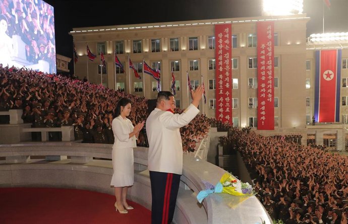 HANDOUT - 25 April 2022, North Korea, Pyongyang: A picture provided by the North Korean state news agency (KCNA) on 26 April 2022, shows North Korean leader Kim Jong-un (R), alongside his wife, Ri Sol-ju, waving during a military parade at Kim Il-sung S