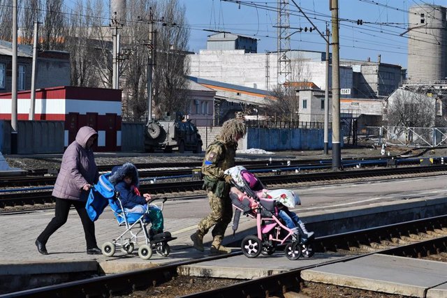 Archivo - Una mujer y un militar son vistos ayudando a varios niños a subirse a un tren en Ucrania en el marco de la invasión rusa