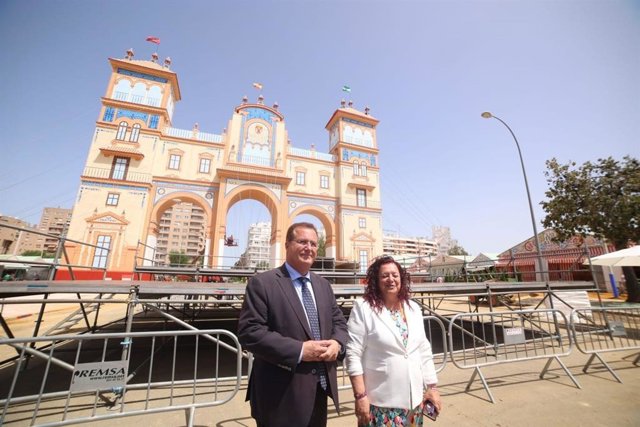 Juan Carlos Cabrera, delegado de Fiestas Mayores, junto a la portada de la Feria de Abril, con la delegada del Distrito Triana-Los Remedios, Encarnación Martínez.