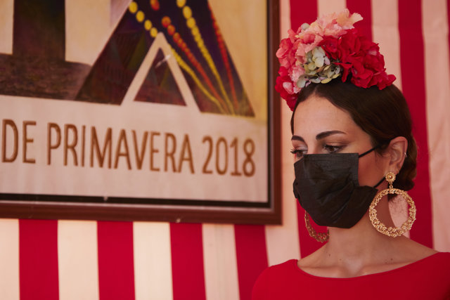 Una flamenca, ataviada con mascarilla, dentro de una caseta durante la colocación del primer tubo de la Portada de la Feria de 2022, a 17 de diciembre de 2021 en Sevilla (Andalucía, España)