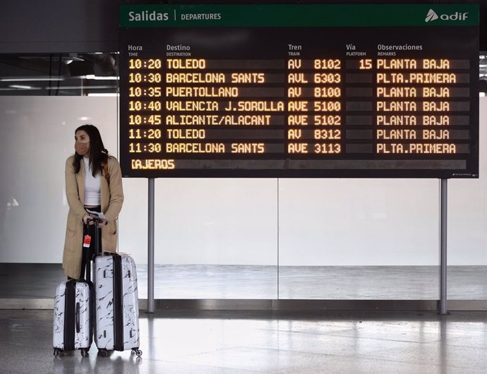Una mujer, con maletas, junto a un panel de salidas con diferentes destinos en Atocha