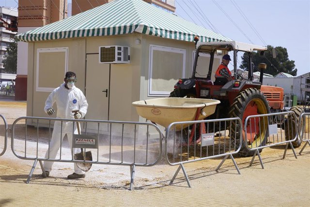 Varios operarios echan cloruro en el albero para evitar el levantamiento de polvo antes del inicio de la Feria de Abril 2022 en el Real de la Feria, a 29 de abril de 2022 en Sevilla (Andalucía, España)